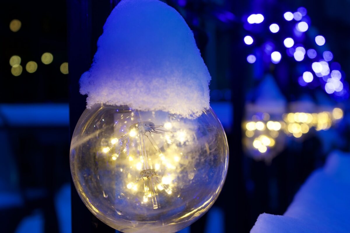 a detailed interior of light bulb with snow on top and bokeh blue and gold in the distance
